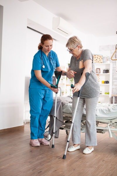 femme âgée infirmière avec réadaptation sur les genoux