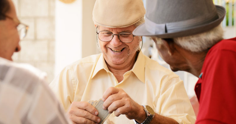 счастливые пожилые мужчины, играющие в карты в активном старшем сообществе