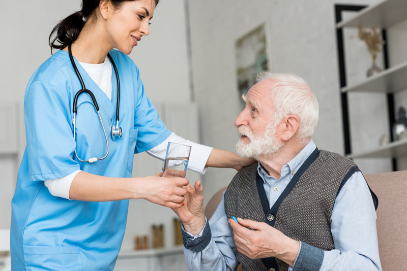медсестра дает стакан воды пожилому человеку с деменцией