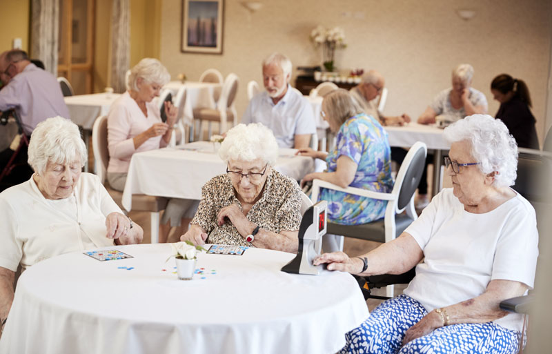 personas mayores jugando al bingo en un apartamento independiente para personas mayores