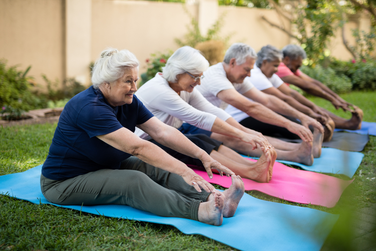 cheerful seniors exercising on mats in assisted living