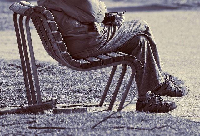 高齢者のアパートを見つけるのを待っている公園のベンチで老人