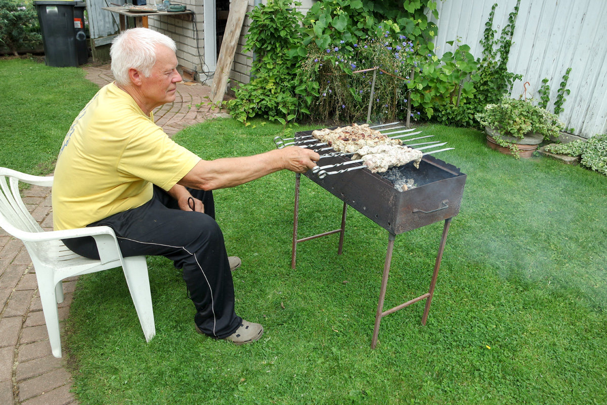 senior man grilling meat in his backyard