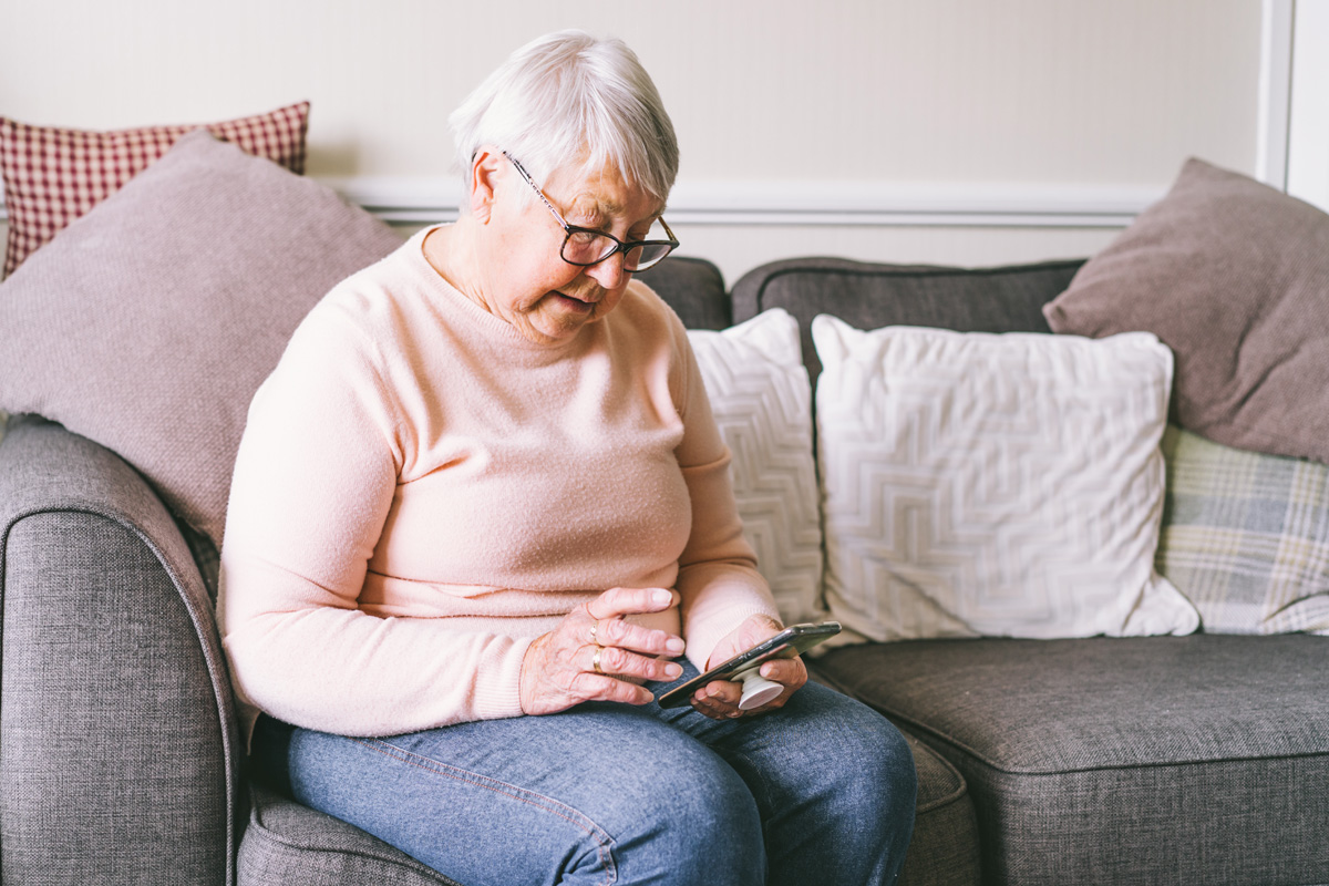 femme âgée utilisant un smartphone pour chercher des appartements pour personnes âgées