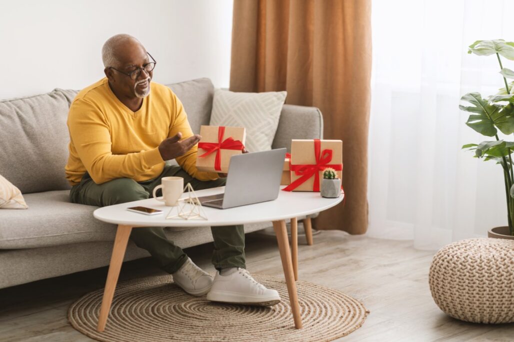 senior black man showing gift on video call